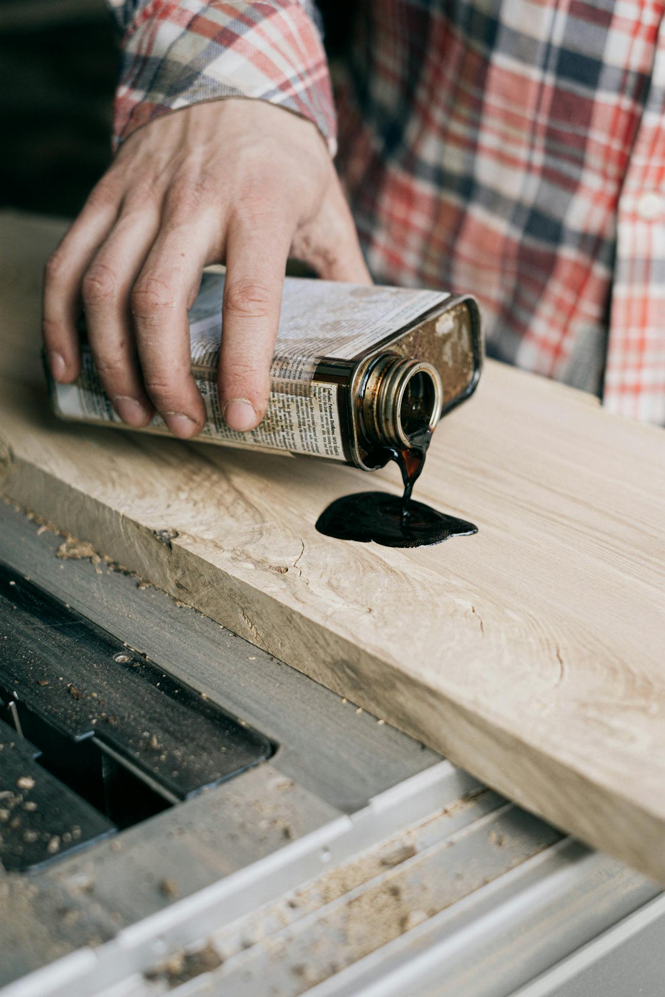 A craftsman applies varnish to a wooden plank, showcasing woodworking skills.